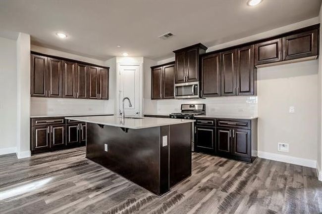 Kitchen featuring visible vents, a sink, light countertops, wood finished floors, and stainless steel appliances | Image 10