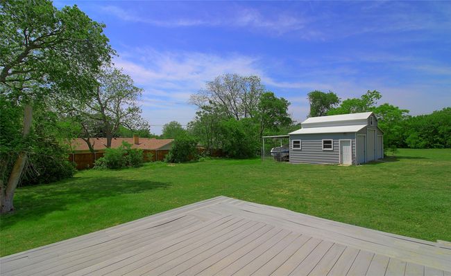 Wooden terrace featuring a storage shed, a lawn, and an outbuilding | Image 26