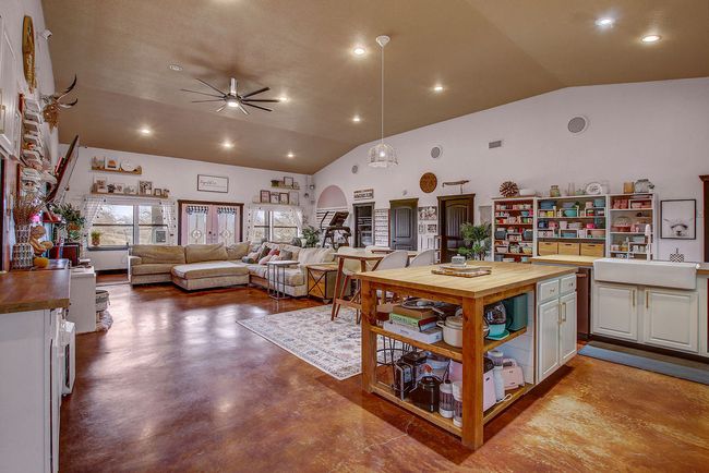 Kitchen with arched walkways, ceiling fan, a sink, wooden counters, and open shelves | Image 13