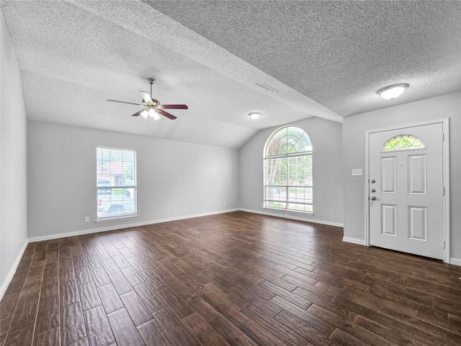 Entrance foyer featuring healthy amount of natural light, dark wood-style floors, ceiling fan, vaulted ceiling, and baseboards | Image 10