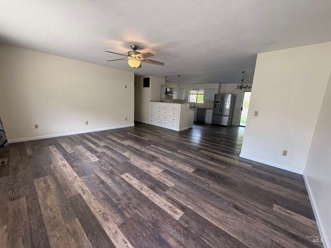 Unfurnished living room featuring dark wood-style floors, ceiling fan, a textured ceiling, and a chandelier | Image 18