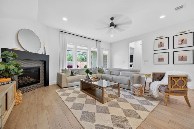 Expansive living room with vaulted ceilings, recessed lighting, and wide-open sightlines into surrounding rooms. Large windows and a glass door create a seamless connection to the backyard. | Image 8