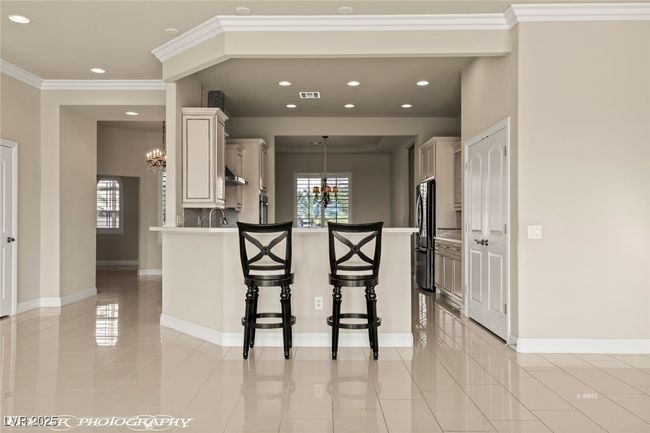 Kitchen with freestanding refrigerator, an inviting chandelier, a kitchen bar, a peninsula, and visible vents | Image 23