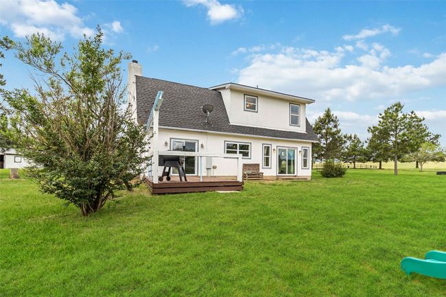 Back of property with stucco siding, a chimney, a deck, a shingled roof, and a yard | Image 28