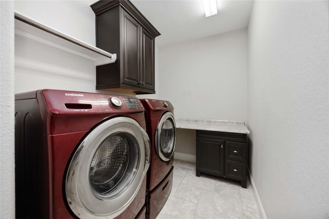 Spacious laundry area with ample countertop space for folding and organization. | Image 39
