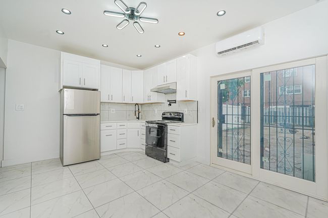 Kitchen with freestanding refrigerator, black range with electric cooktop, a wall mounted air conditioner, recessed lighting, and under cabinet range hood | Image 14