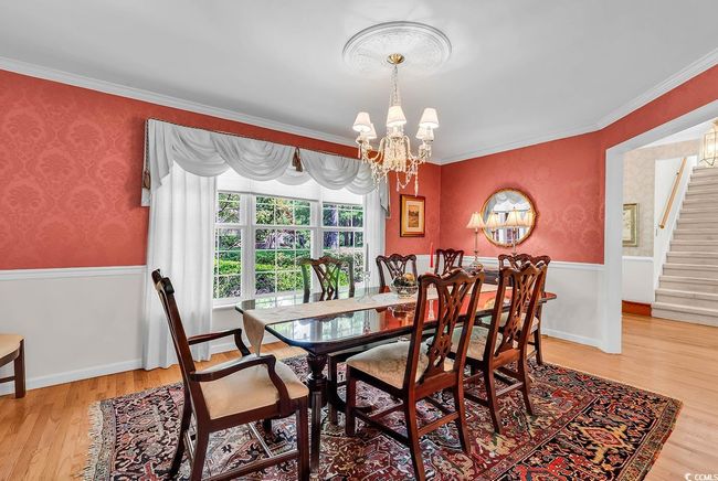 Dining room featuring a chandelier, light wood-type flooring, stairs, crown molding, and wallpapered walls | Image 7