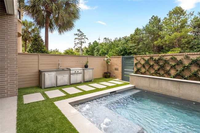 This stylish escape combines sleek design with functional luxury. The outdoor kitchen is equipped with premium DCS appliances, including a sink, weather-resistant refrigerator, and a 30” flat grill with direct natural gas—perfect for effortless al fresco entertaining. | Image 36