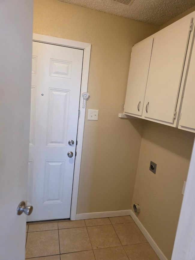 Laundry room with electric dryer hookup, light tile patterned floors, and cabinet space | Image 7