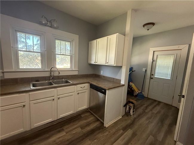 Kitchen with stainless steel dishwasher, white cabinets, dark wood-style flooring, and dark countertops | Image 10