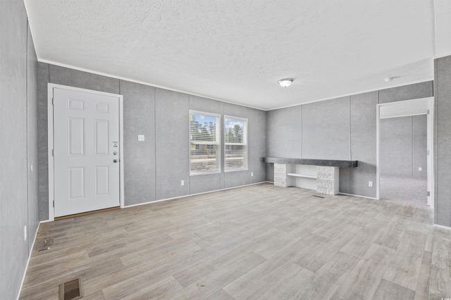 Unfurnished living room featuring wood finished floors, a textured ceiling, and ornamental molding | Image 11