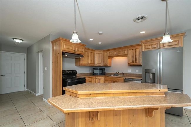 Kitchen featuring black appliances, light tile patterned flooring, visible vents, and under cabinet range hood | Image 11