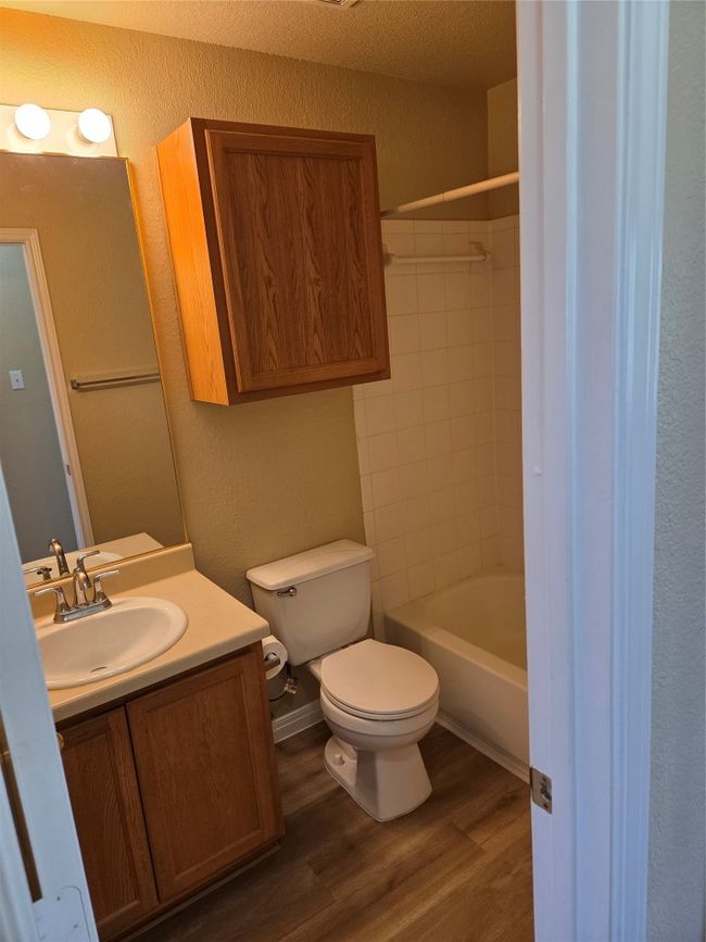 Full bathroom featuring a textured wall, vanity, wood finished floors, and shower combination | Image 26
