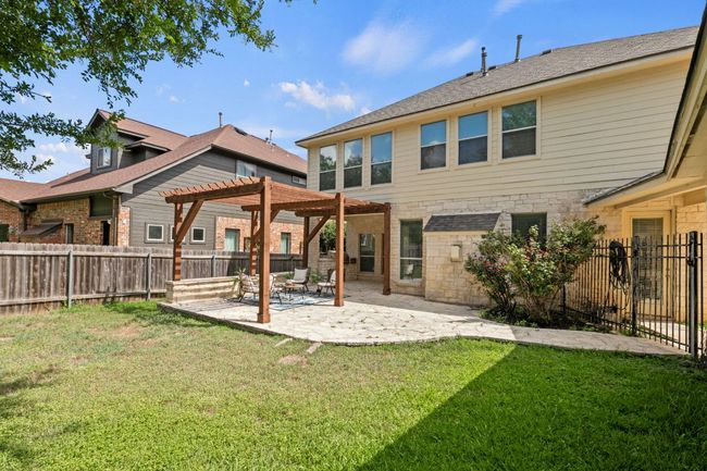 Rear view of property with a pergola, a patio, a fenced backyard, and stone siding | Image 33