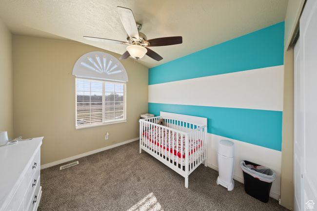 Carpeted bedroom with a nursery area, a ceiling fan, a closet, and vaulted ceiling | Image 19