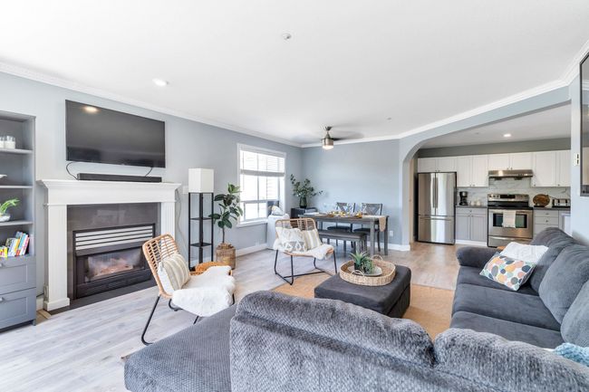 Living area featuring arched walkways, light wood-style flooring, a fireplace with flush hearth, and crown molding | Image 10
