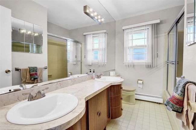 Bathroom featuring baseboard heating, tile patterned flooring, vanity, toilet, and walk in shower | Image 26