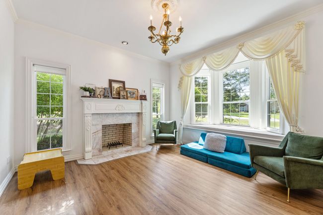 Living room with luxury vinyl planking floors, plenty of natural light, a chandelier, a high end fireplace, and crown molding | Image 10