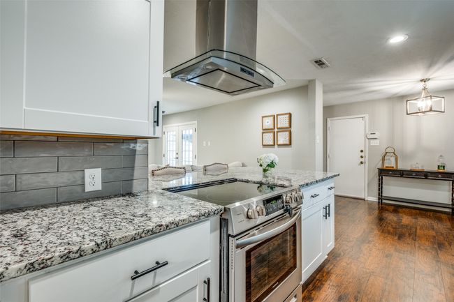 Kitchen featuring island range hood, electric stove, light stone counters, white cabinets, and tasteful backsplash | Image 21
