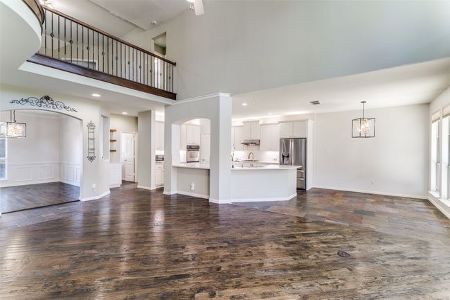 Unfurnished living room featuring dark wood finished floors, arched walkways, a towering ceiling, a chandelier, and recessed lighting | Image 8