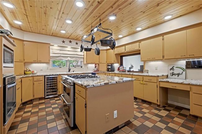 Kitchen featuring beverage cooler, wood ceiling, appliances with stainless steel finishes, dark floors, and recessed lighting | Image 7