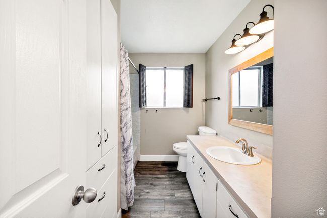 Bathroom with wood finished floors, toilet, vanity, baseboards, and a shower with shower curtain | Image 14