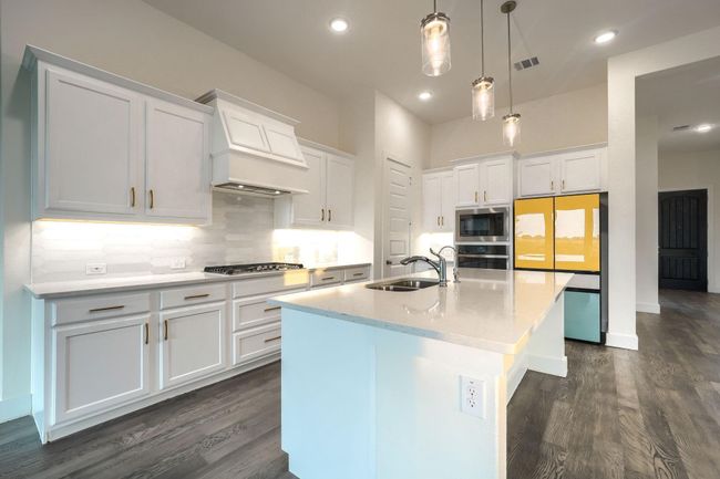Kitchen featuring appliances with stainless steel finishes, a sink, dark wood-style floors, premium range hood, and an island with sink | Image 9