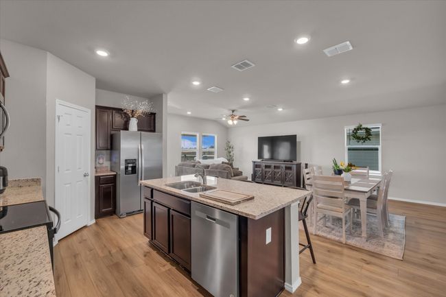 Kitchen with stainless steel appliances, a sink, light wood finished floors, dark brown cabinetry, and a center island with sink | Image 22