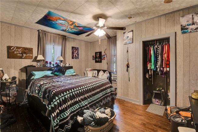 Bedroom featuring wood walls, wood-type flooring, and a ceiling fan | Image 15