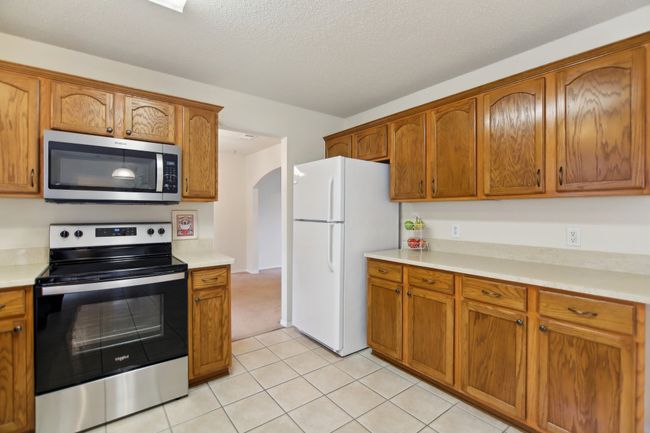 Kitchen with brown cabinetry, stainless steel appliances, and arched walkways | Image 10