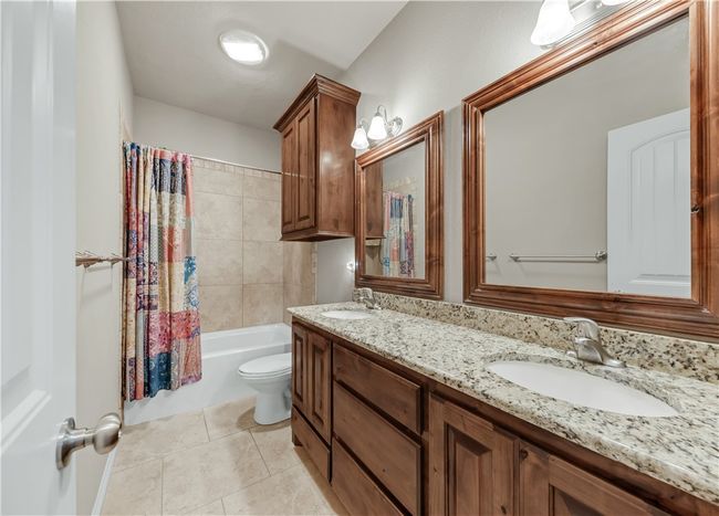 Full bath with double vanity, tile patterned flooring, toilet, and shower / tub combo with curtain | Image 26