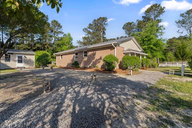 View of front of property with brick siding, an outbuilding, and gravel driveway | Image 4