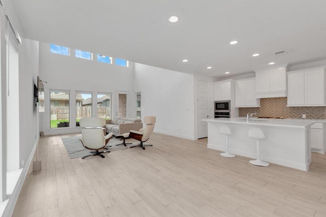 Kitchen featuring decorative backsplash, open floor plan, light countertops, recessed lighting, and light wood-type flooring | Image 14