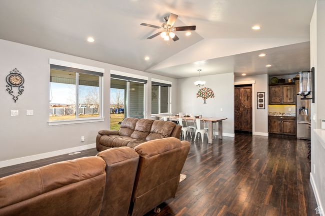 Living room with baseboards, a ceiling fan, vaulted ceiling, and dark wood-style floors | Image 7