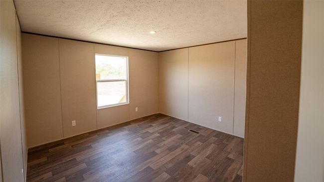 Empty room featuring dark wood finished floors, a textured ceiling, and a decorative wall | Image 19
