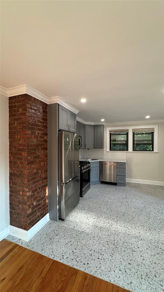 Kitchen with gray cabinetry, stainless steel appliances, light countertops, brick wall, and recessed lighting | Image 8