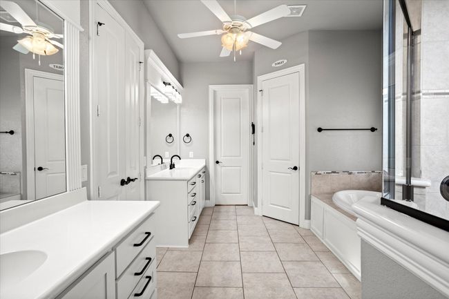 Full bath featuring ceiling fan, two vanities, a bath, and tile patterned flooring | Image 20