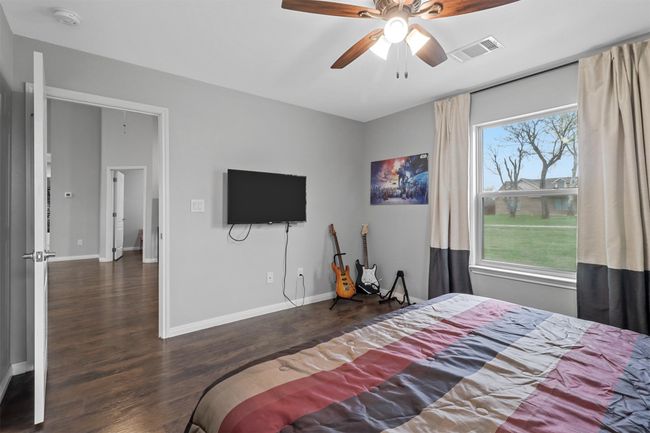 Bedroom with baseboards, visible vents, wood finished floors, and ceiling fan | Image 15