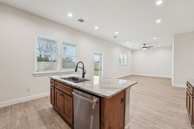 Kitchen featuring a sink, light stone countertops, dishwasher, and wood plank tile floor | Image 16