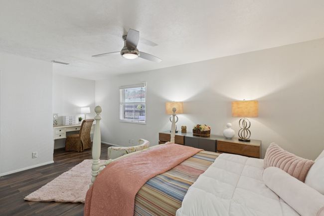 Bedroom with wood finished floors, an office area, and a ceiling fan | Image 9