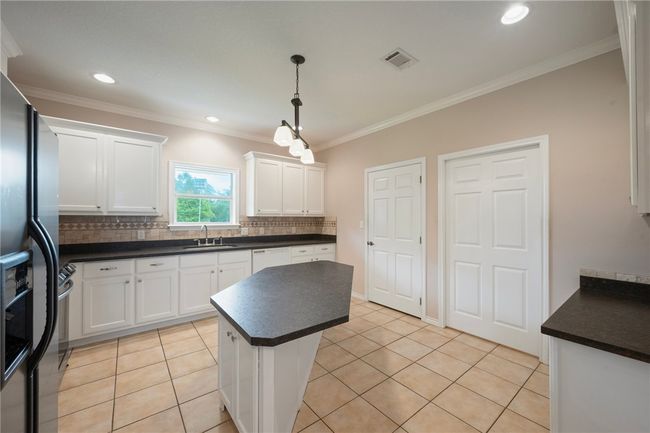 Kitchen featuring a sink, tasteful backsplash, dark countertops, white cabinets, and dishwasher | Image 9