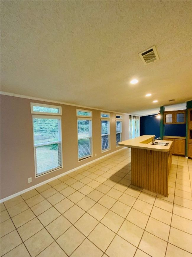 Kitchen featuring visible vents, recessed lighting, crown molding, an island with sink, and light tile patterned floors | Image 8