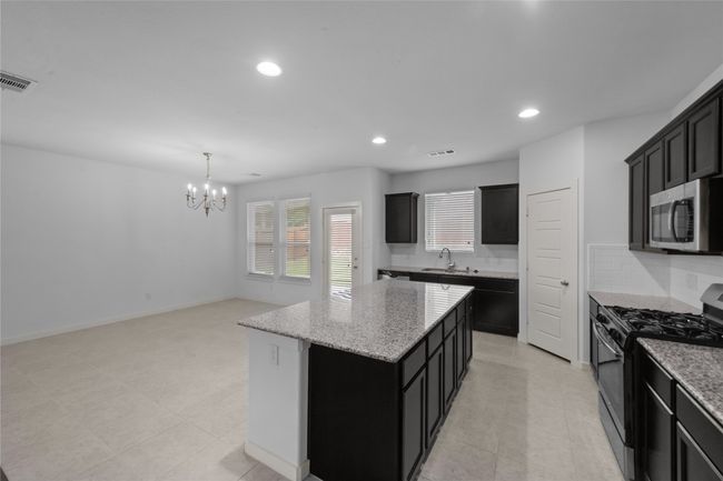 Kitchen with gas range oven, stainless steel microwave, dark cabinets, a kitchen island, and recessed lighting | Image 15