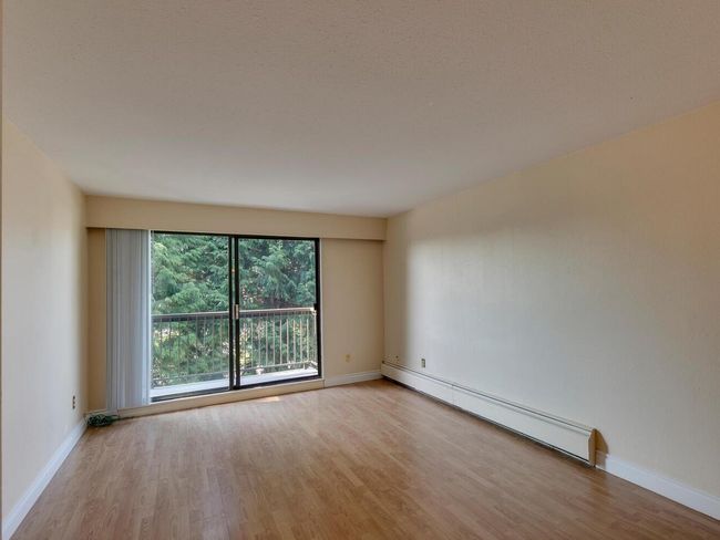 Empty room with a baseboard heating unit, baseboards, and wood finished floors | Image 5