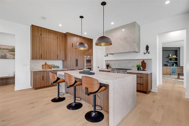 Kitchen featuring light wood finished floors, a center island, tasteful backsplash, a breakfast bar area, and recessed lighting | Image 10