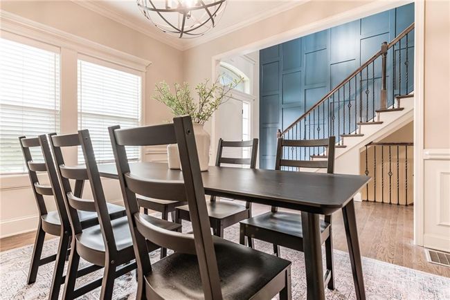 Dining room with a chandelier, healthy amount of natural light, crown molding, light wood-style flooring, and stairway | Image 5