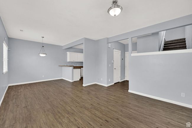 Unfurnished living room featuring dark wood-style floors and stairs | Image 15