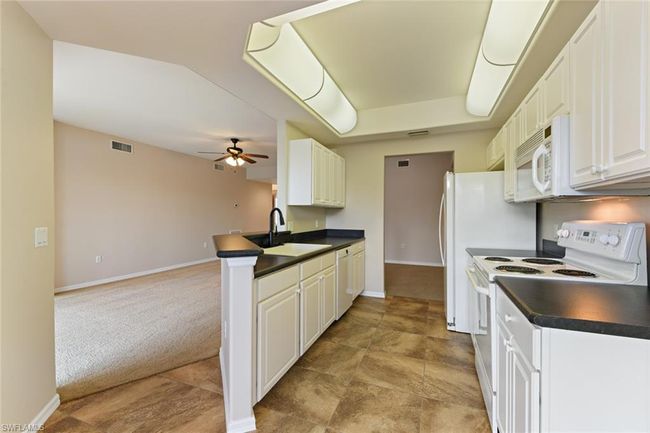 Kitchen featuring a sink, light carpet, white appliances, dark countertops, and ceiling fan | Image 19
