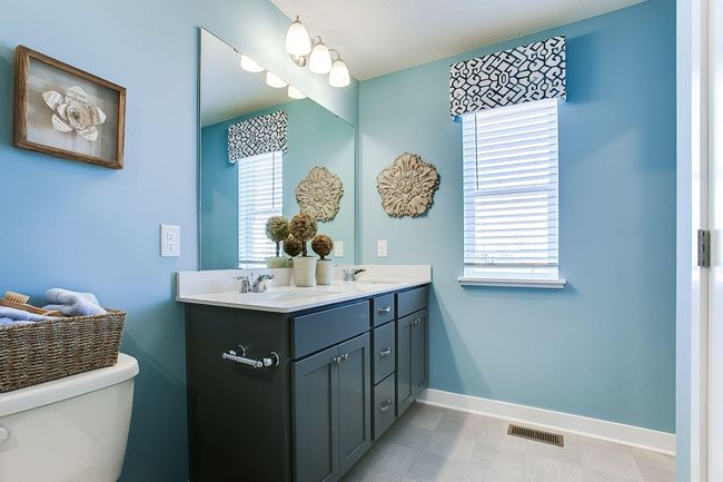 A peak inside the bathroom off the Primary Suite. Notice the extra high cabinets and double-bowl Quartz covered vanity with loads of storage! Photo is of model home. Colors and options may vary. Ask Sales Agent for details. | Image 25