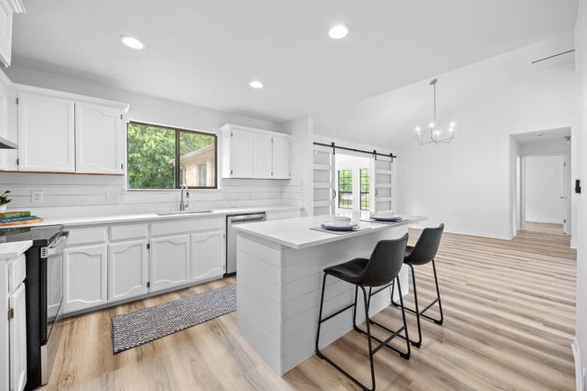 Kitchen with electric range, stainless steel dishwasher, plenty of natural light, white cabinetry, and recessed lighting | Image 10